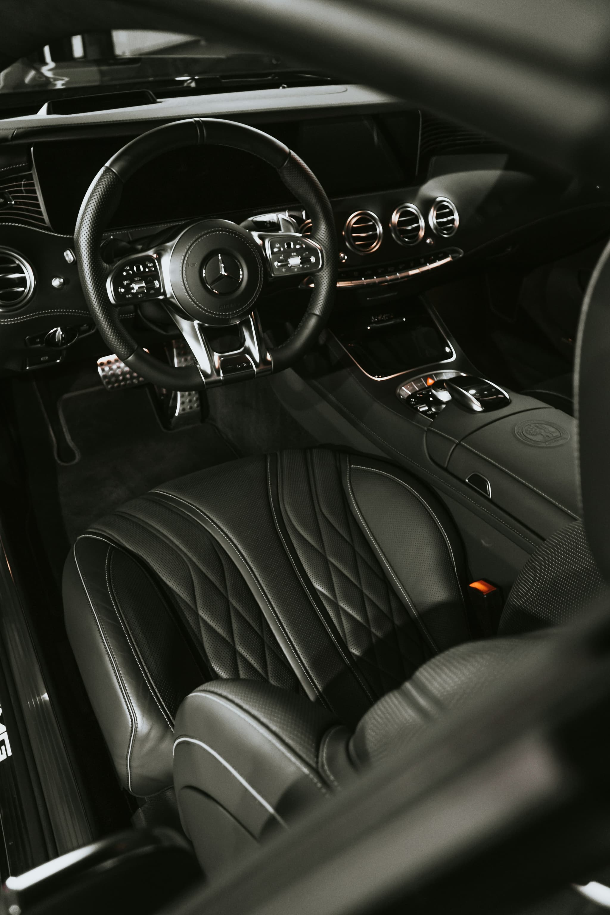 A dark leather vehicle interior in low light